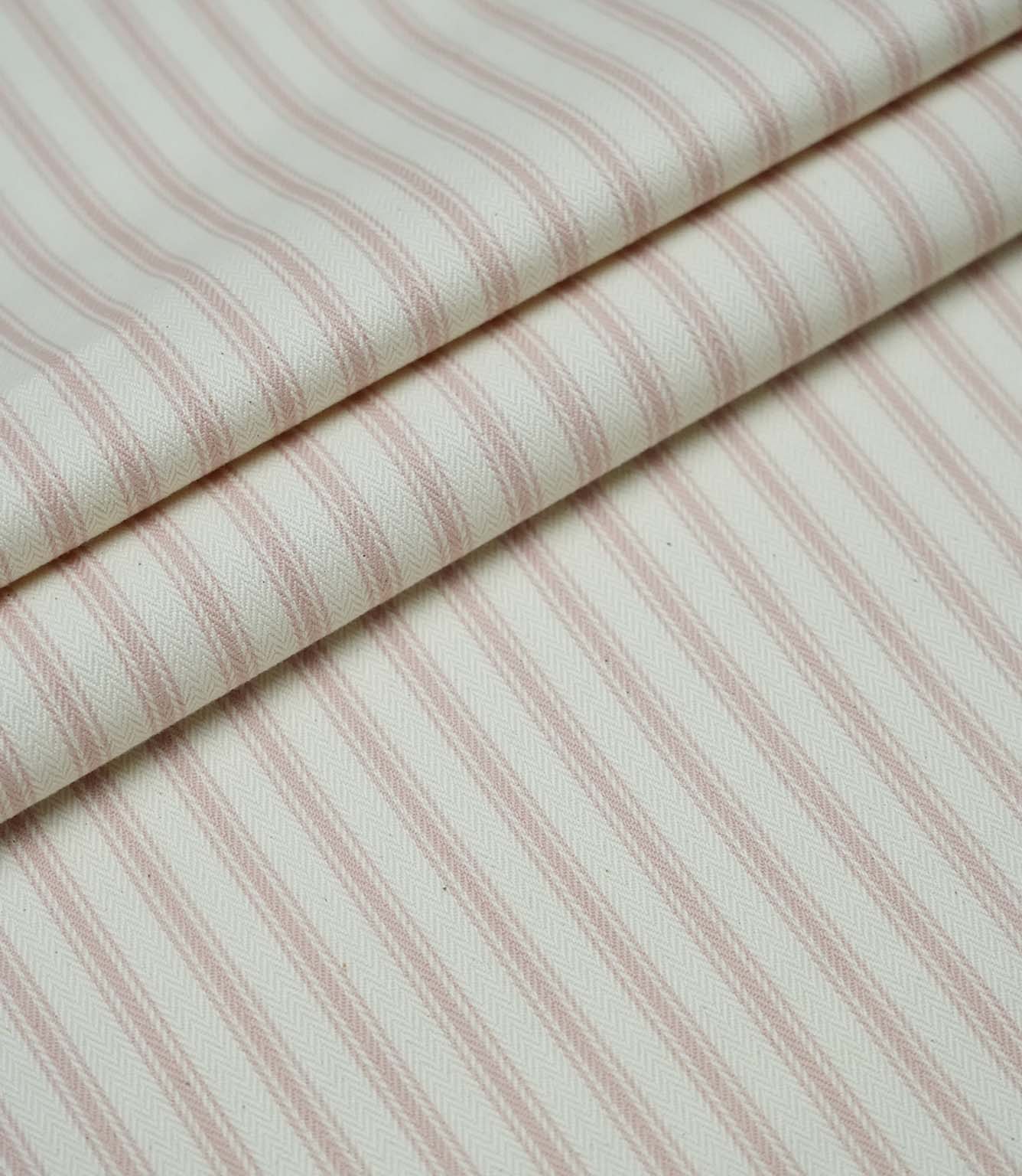 Layered folds of pink ticking stripe fabric displaying the fine herringbone weave and classic striped design.