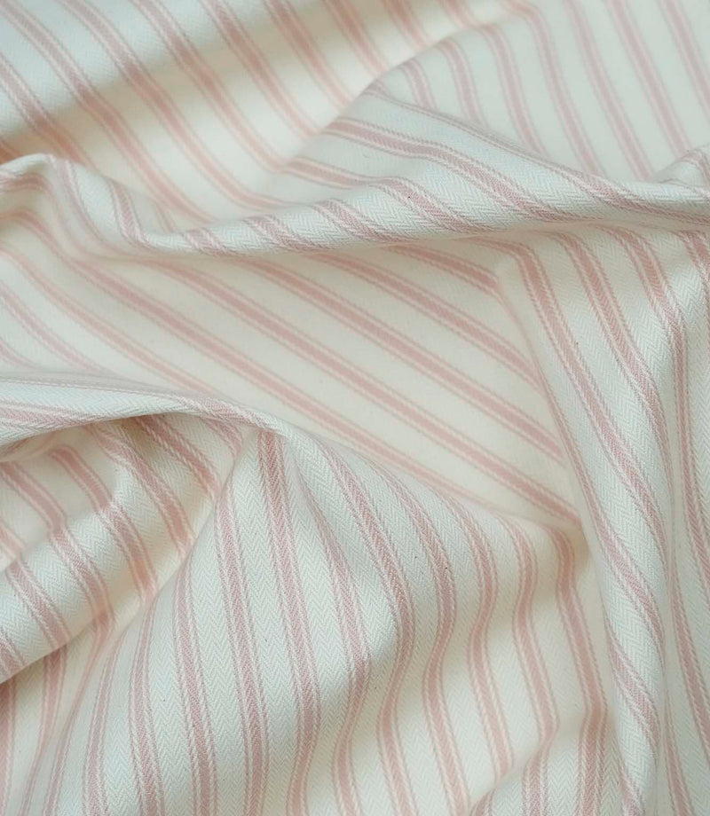 Pink ticking stripe fabric draped to show its soft handle, elegant stripe pattern and woven herringbone texture.