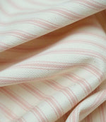 Close-up detail of pink ticking stripe fabric showing the fine woven texture and soft pink stripe pattern.