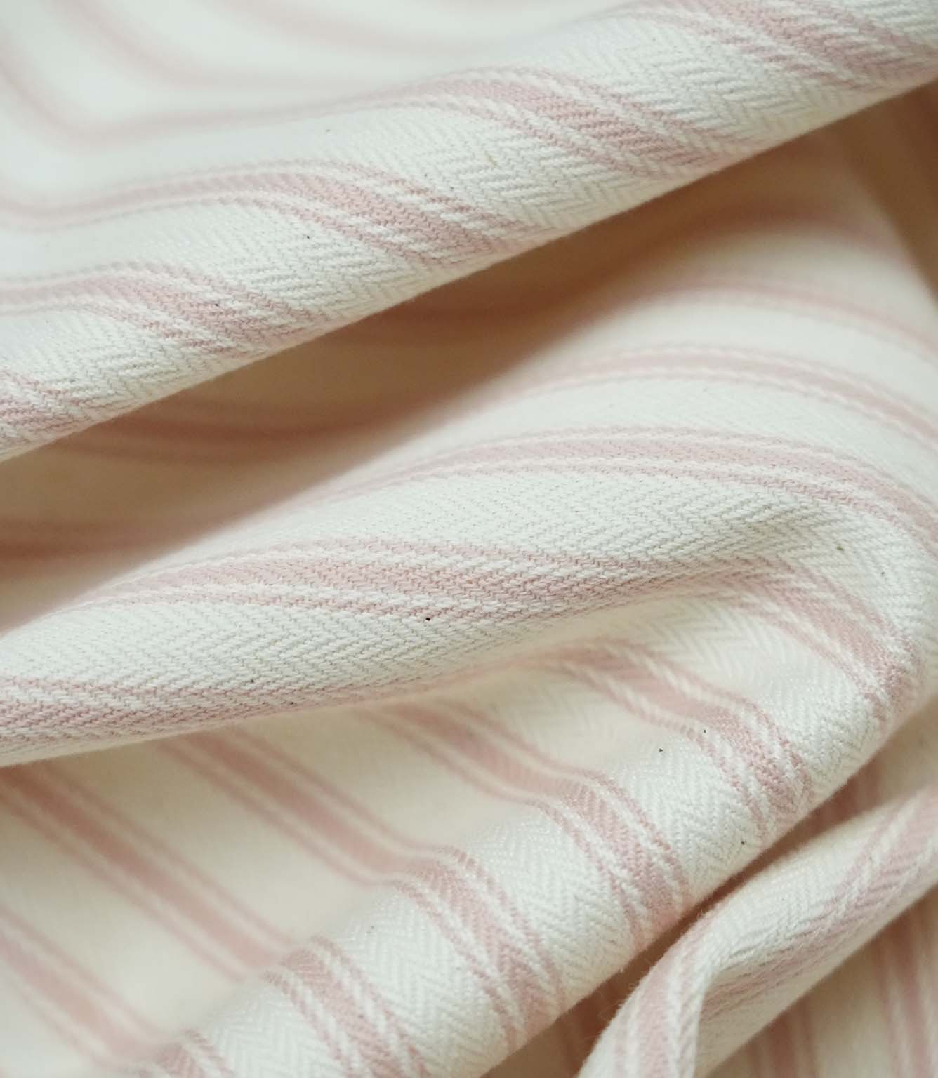 Close-up detail of pink ticking stripe fabric showing the fine woven texture and soft pink stripe pattern.
