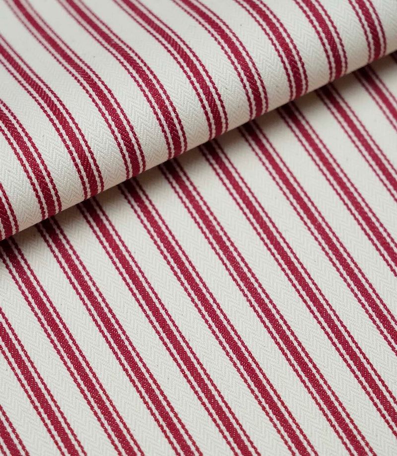 Folded red ticking stripe fabric showcasing the timeless striped pattern and premium woven herringbone finish.