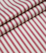 Layered folds of red ticking stripe fabric displaying the fine herringbone weave and classic striped design.