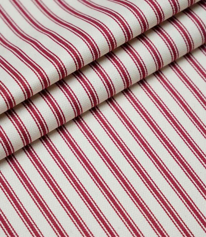 Layered folds of red ticking stripe fabric displaying the fine herringbone weave and classic striped design.