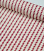 Rolled red ticking stripe fabric highlighting the classic striped design and subtle woven herringbone texture.