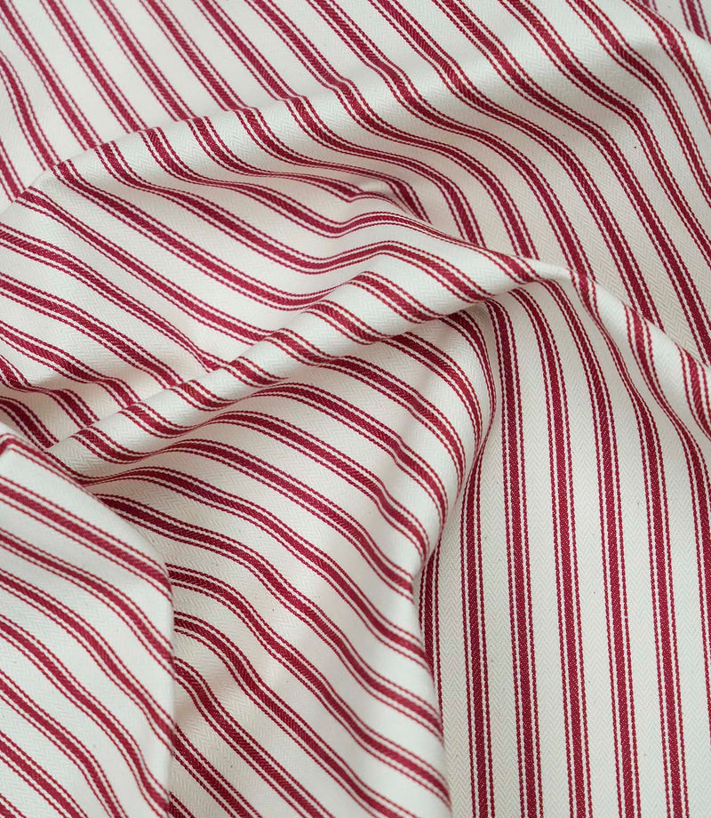 Red ticking stripe fabric draped to show its soft handle, elegant stripe pattern and woven herringbone texture.