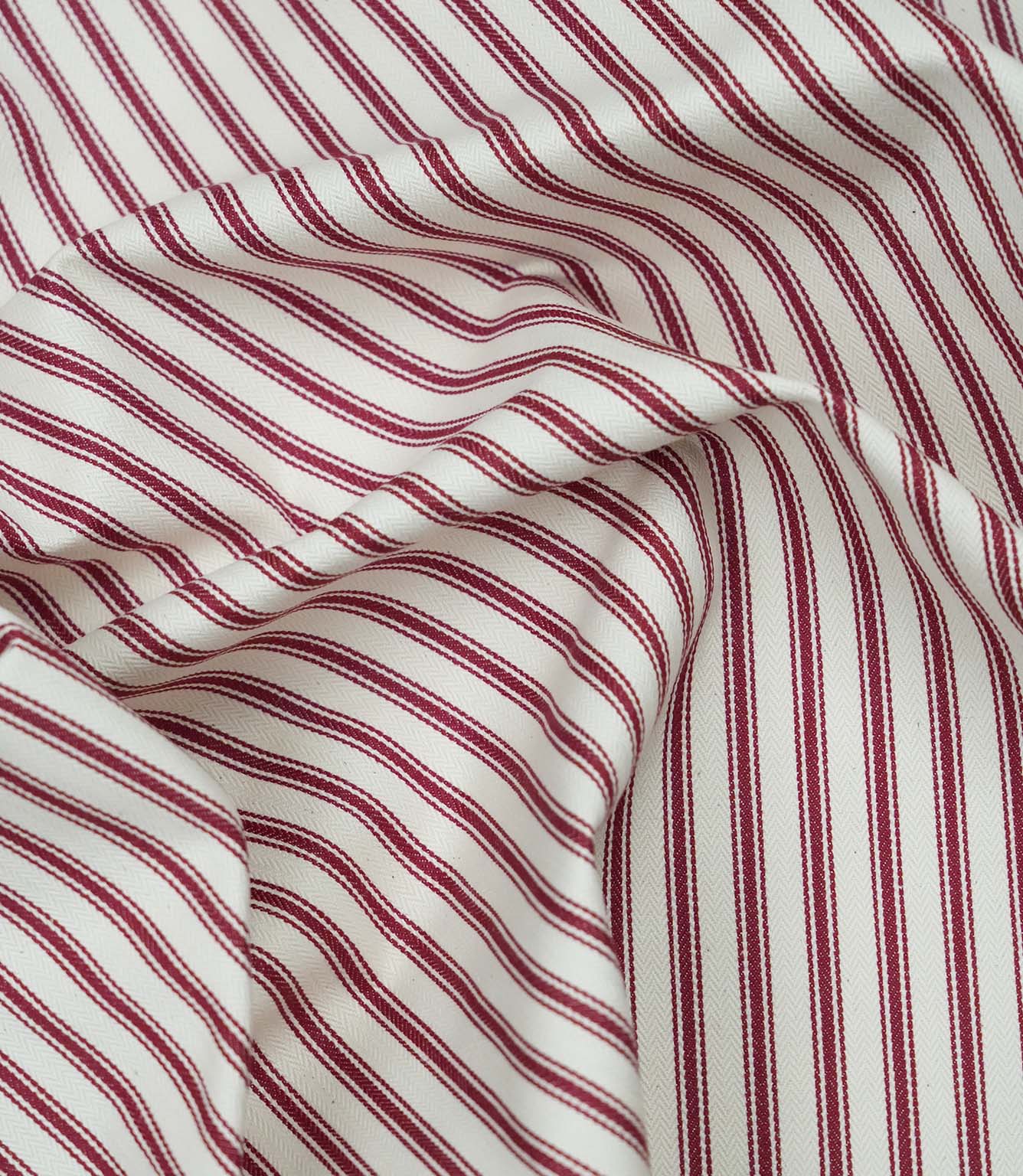 Red ticking stripe fabric draped to show its soft handle, elegant stripe pattern and woven herringbone texture.