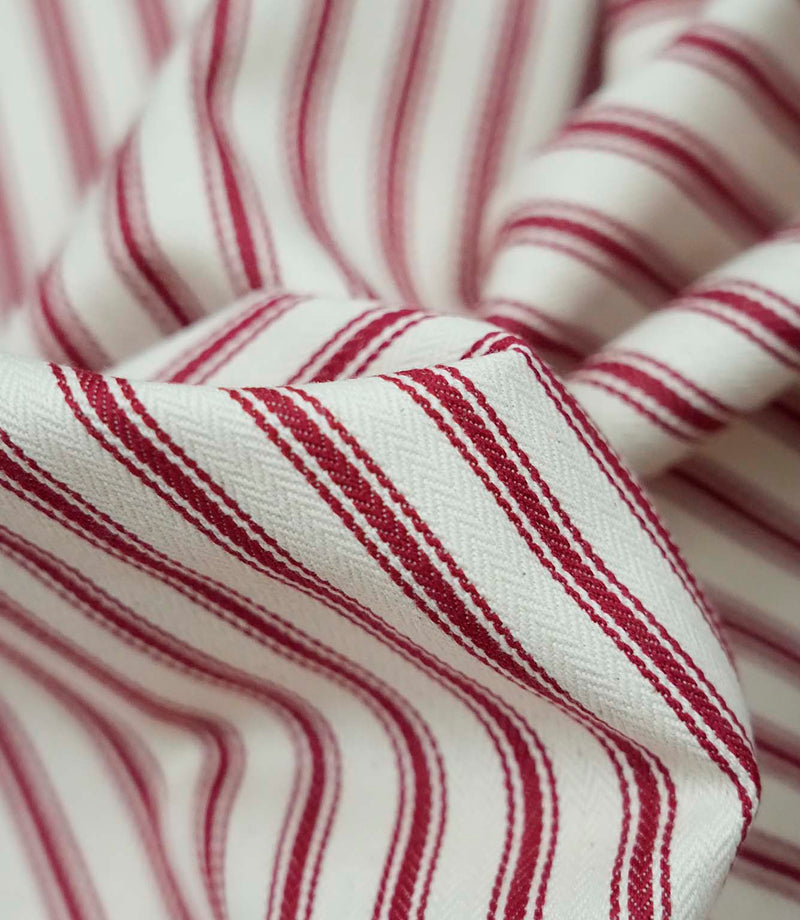 Close-up detail of red ticking stripe fabric showing the fine woven texture and bold red stripe pattern.