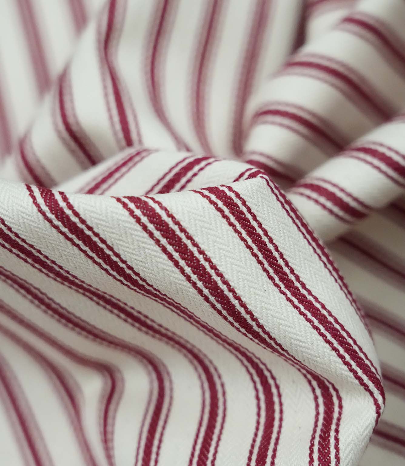 Close-up detail of red ticking stripe fabric showing the fine woven texture and bold red stripe pattern.