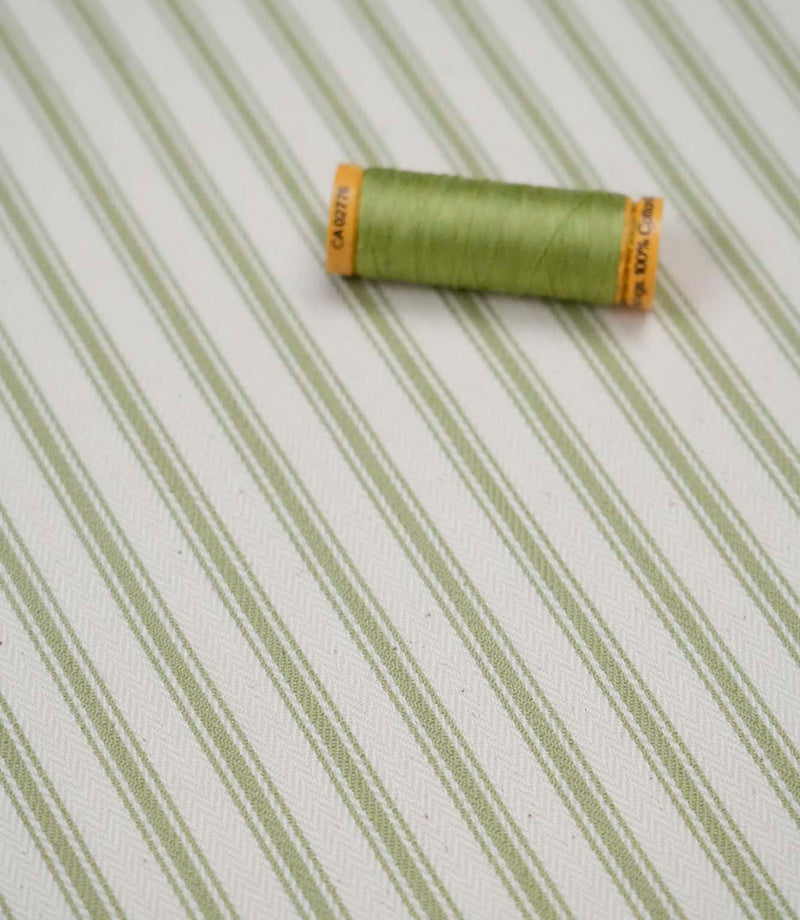Sage green ticking stripe fabric with matching green thread, ideal for upholstery, curtains, blinds and sewing projects.