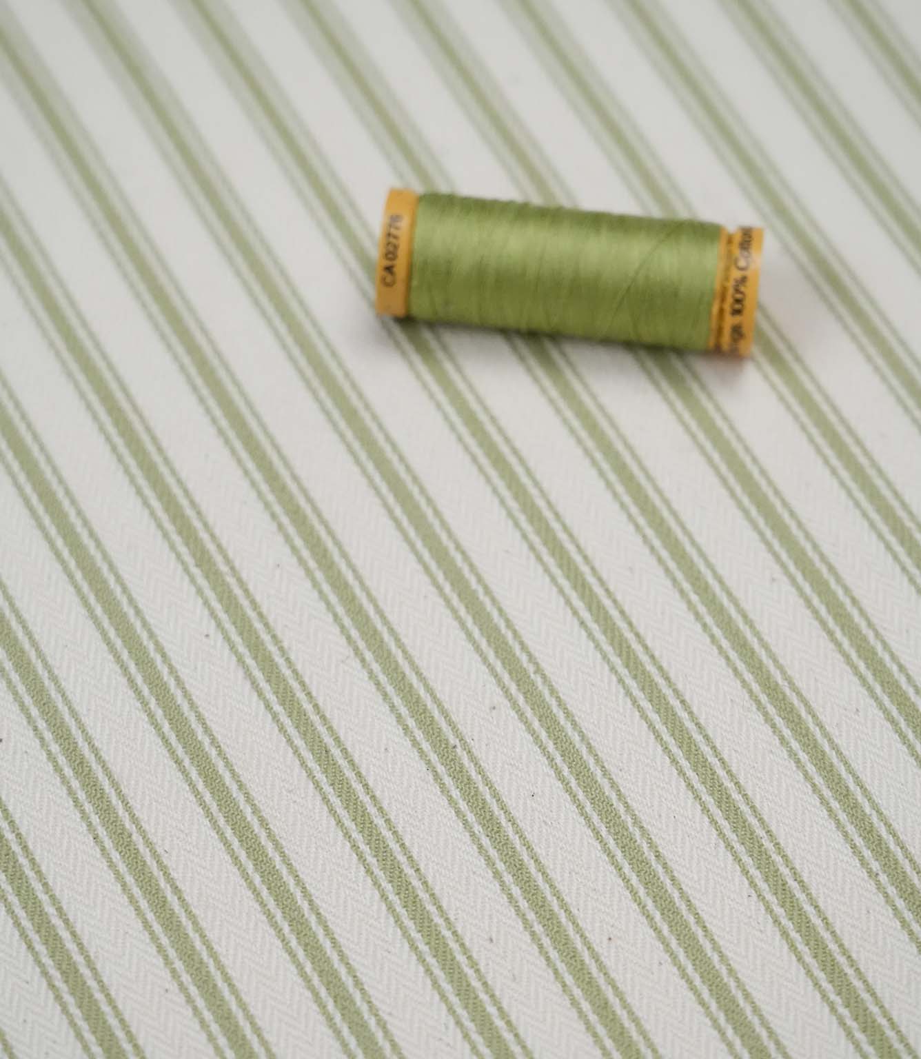 Sage green ticking stripe fabric with matching green thread, ideal for upholstery, curtains, blinds and sewing projects.