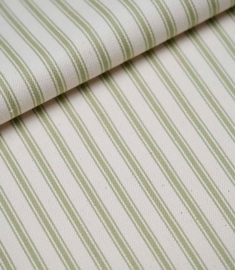 Folded sage green ticking stripe fabric showcasing the timeless striped pattern and premium woven herringbone finish.