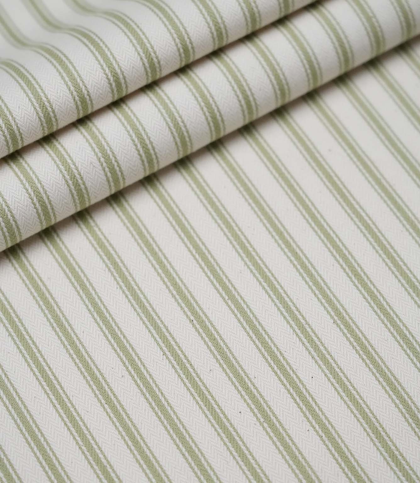 Layered folds of sage green ticking stripe fabric displaying the fine herringbone weave and classic striped design.