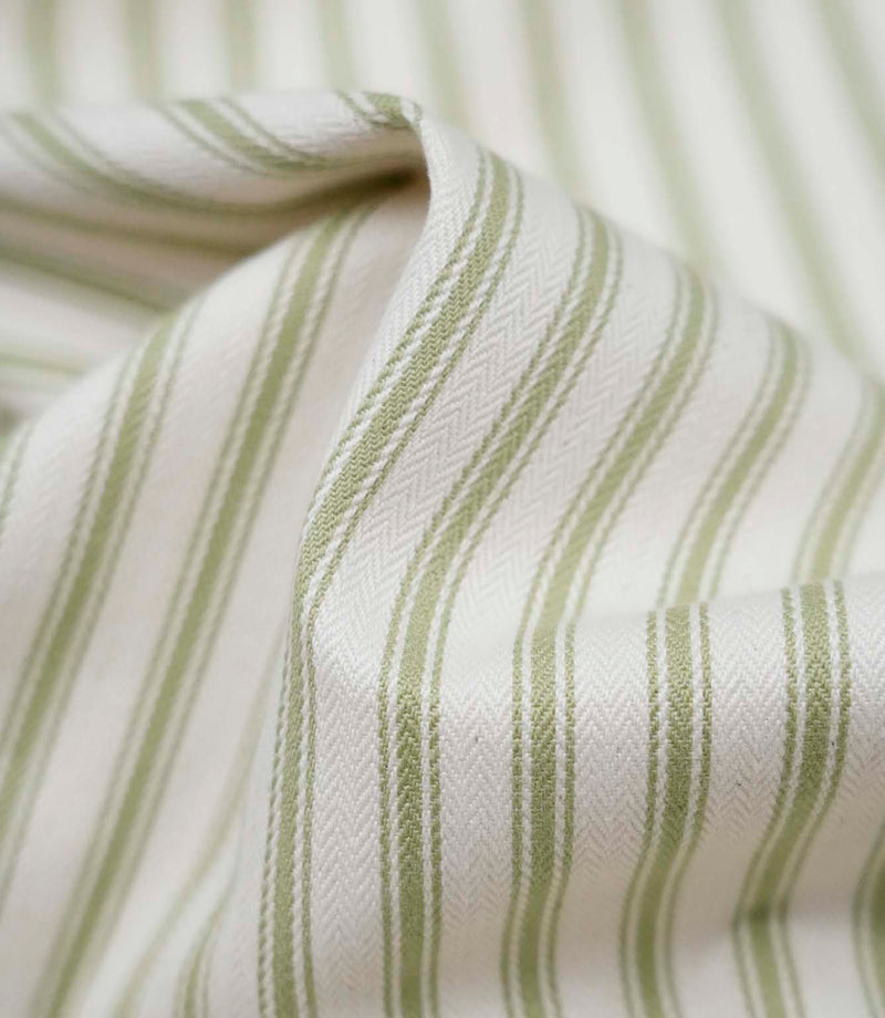Close-up detail of sage green ticking stripe fabric showing the fine woven texture and soft sage green stripe pattern.
