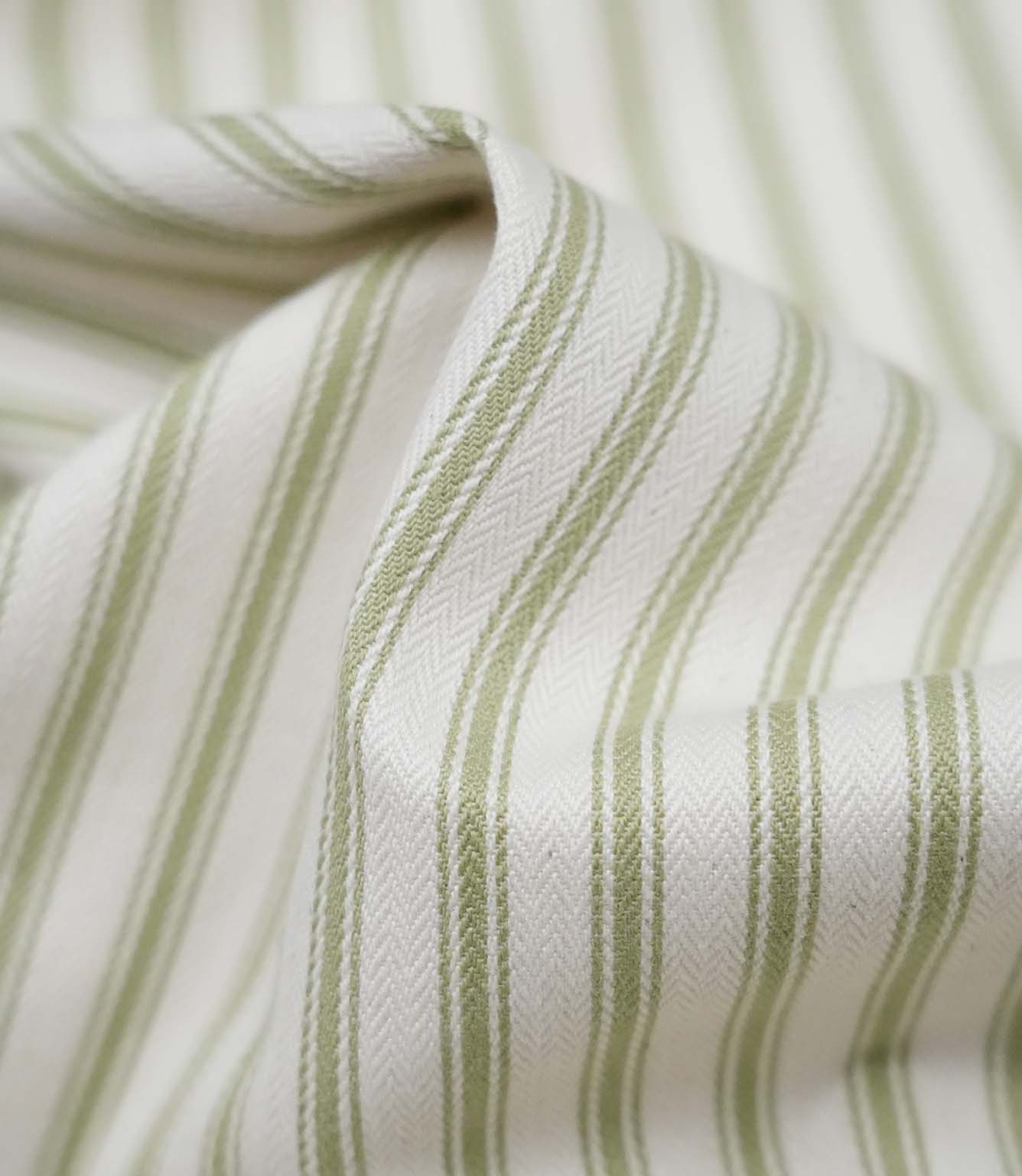 Close-up detail of sage green ticking stripe fabric showing the fine woven texture and soft sage green stripe pattern.