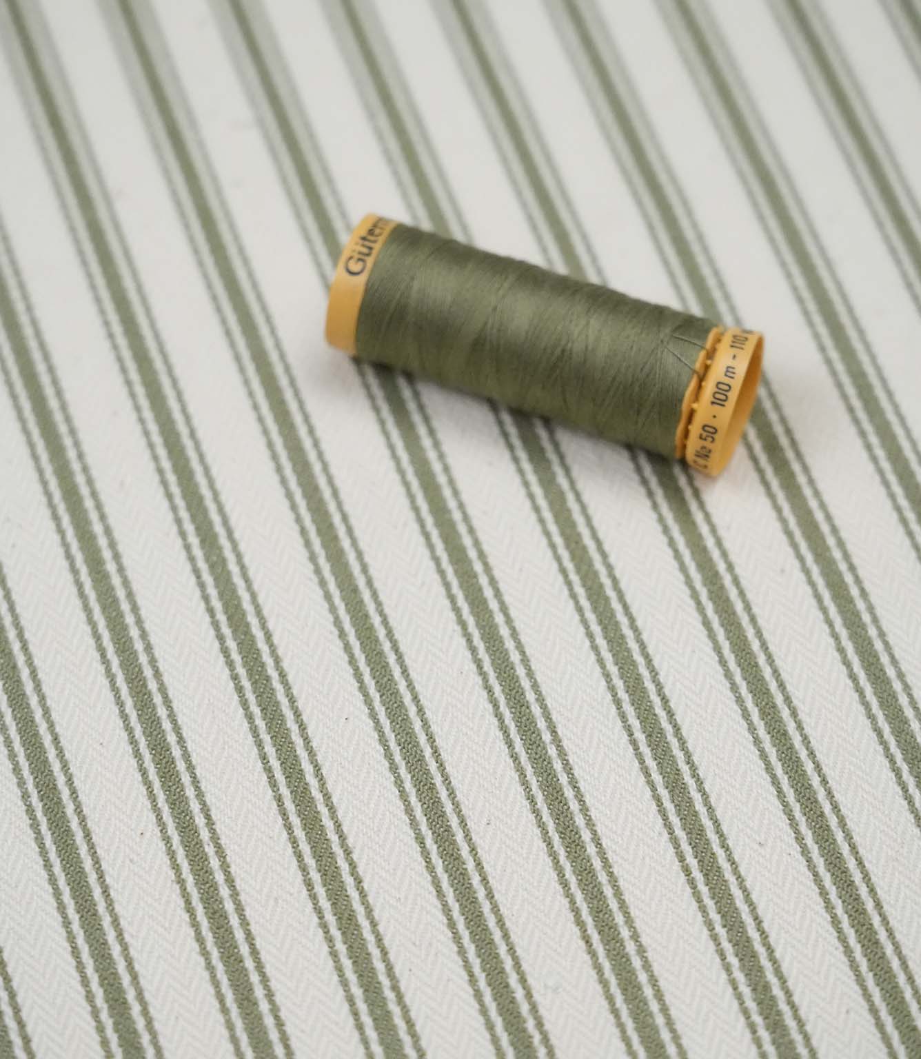 Sap green ticking stripe fabric with matching green thread, ideal for upholstery, curtains, blinds and sewing projects.