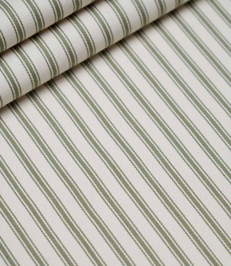 Layered folds of sap green ticking stripe fabric displaying the fine herringbone weave and classic striped design.