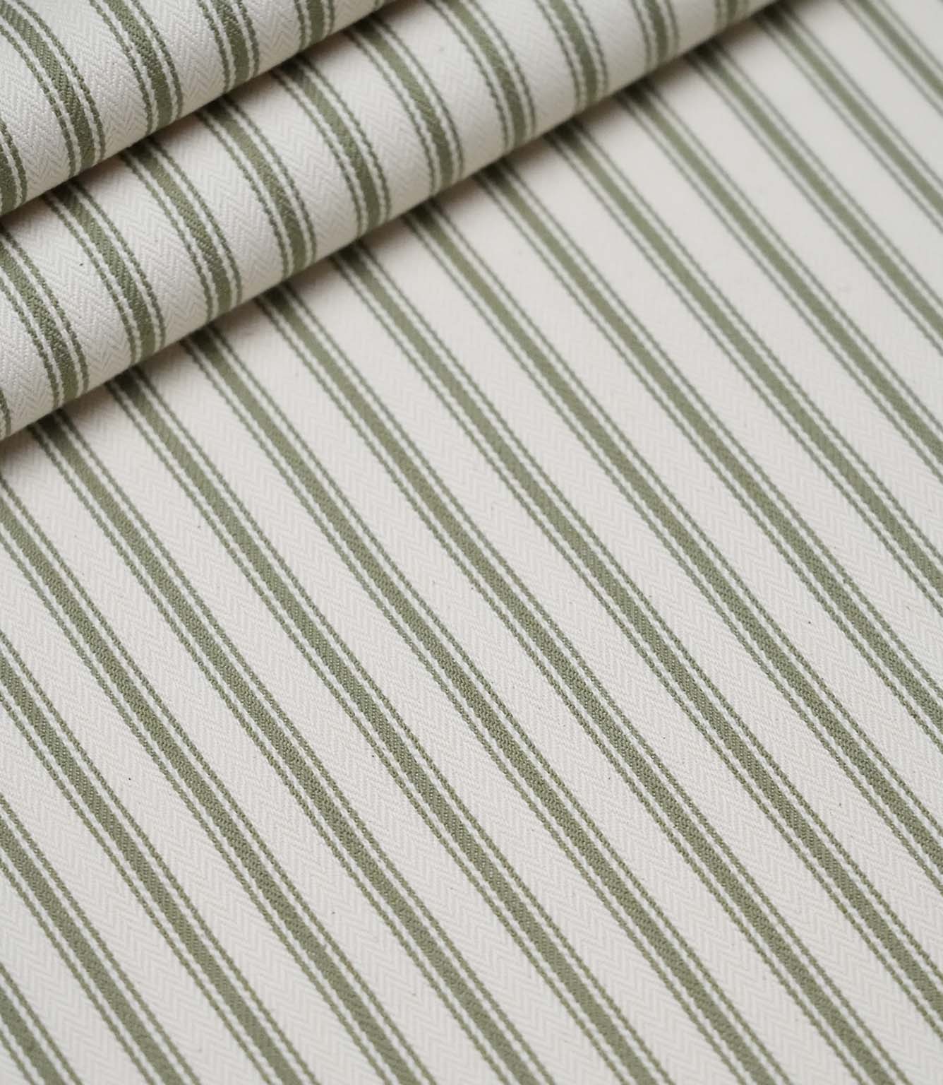Layered folds of sap green ticking stripe fabric displaying the fine herringbone weave and classic striped design.