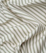 Close-up detail of sap green ticking stripe fabric showing the fine woven herringbone texture and classic green ticking stripes.