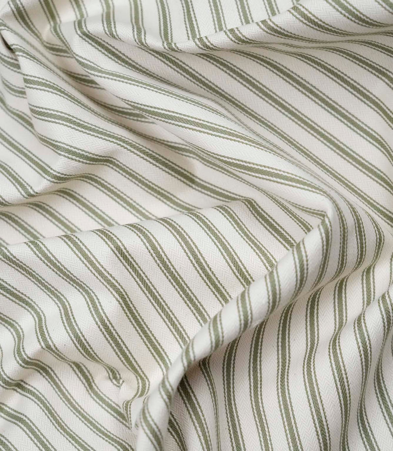 Close-up detail of sap green ticking stripe fabric showing the fine woven herringbone texture and classic green ticking stripes.