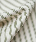Close-up of folded sap green ticking stripe fabric highlighting the soft drape, woven herringbone texture and traditional striped design.