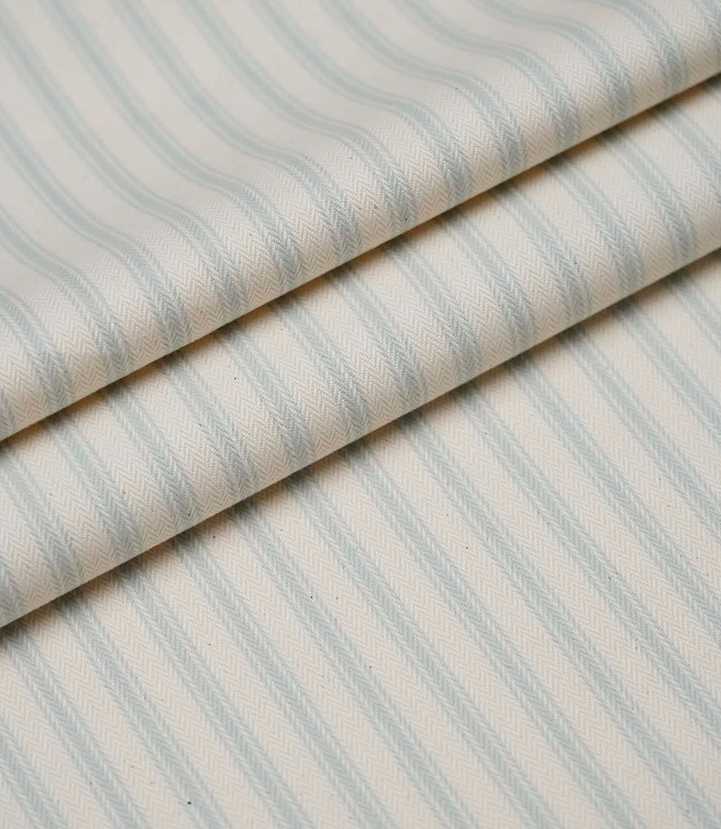 Layered folds of Sea Spray blue ticking stripe fabric showcasing the fine woven herringbone texture and elegant stripes.