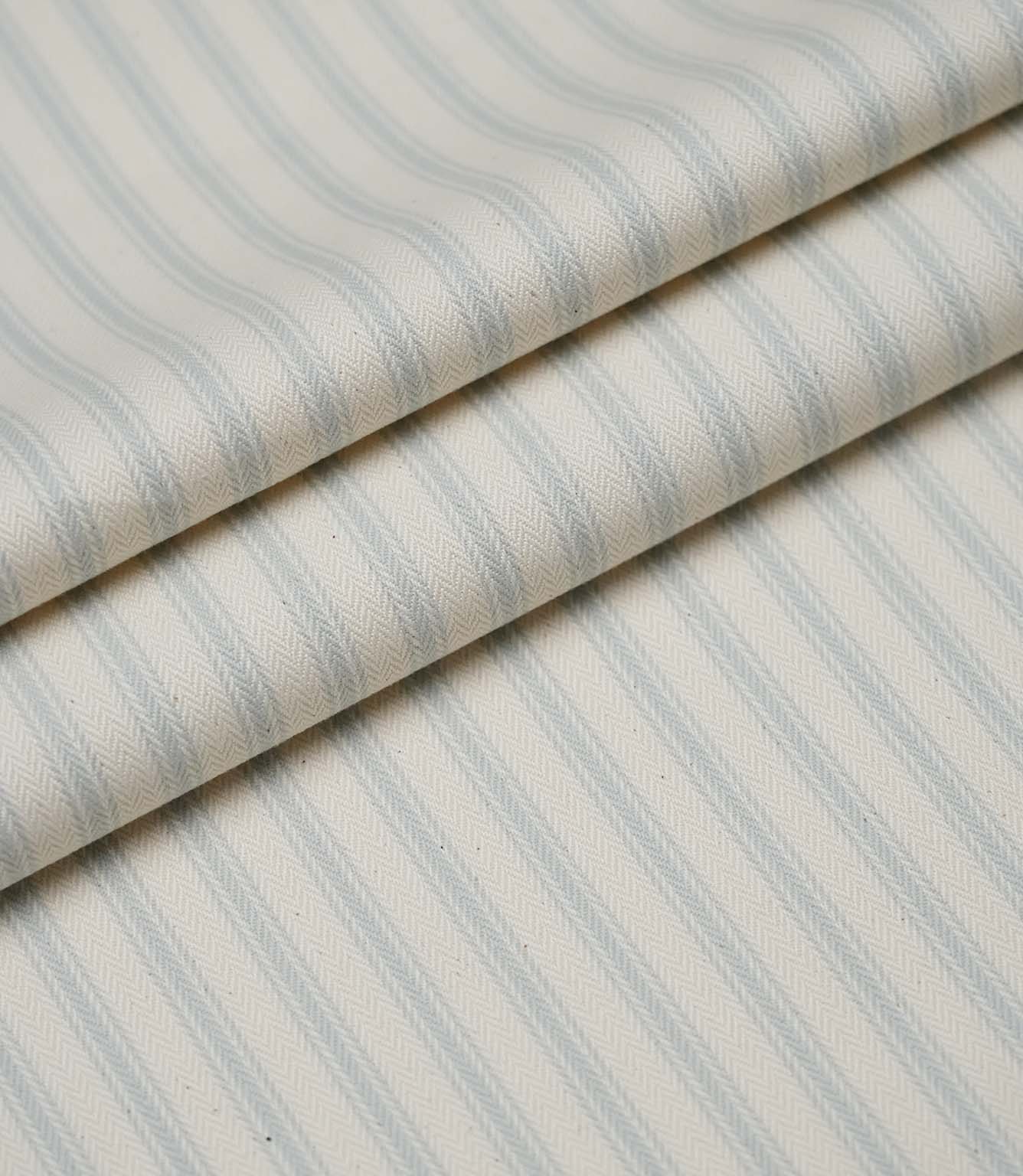 Layered folds of Sea Spray blue ticking stripe fabric showcasing the fine woven herringbone texture and elegant stripes.