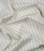 Sea Spray ticking stripe fabric draped to display its soft handle, subtle herringbone weave and timeless striped pattern.