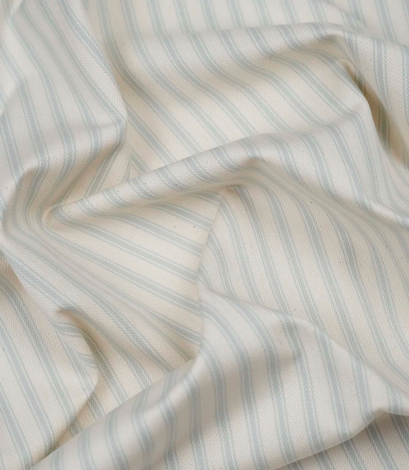 Sea Spray ticking stripe fabric draped to display its soft handle, subtle herringbone weave and timeless striped pattern.