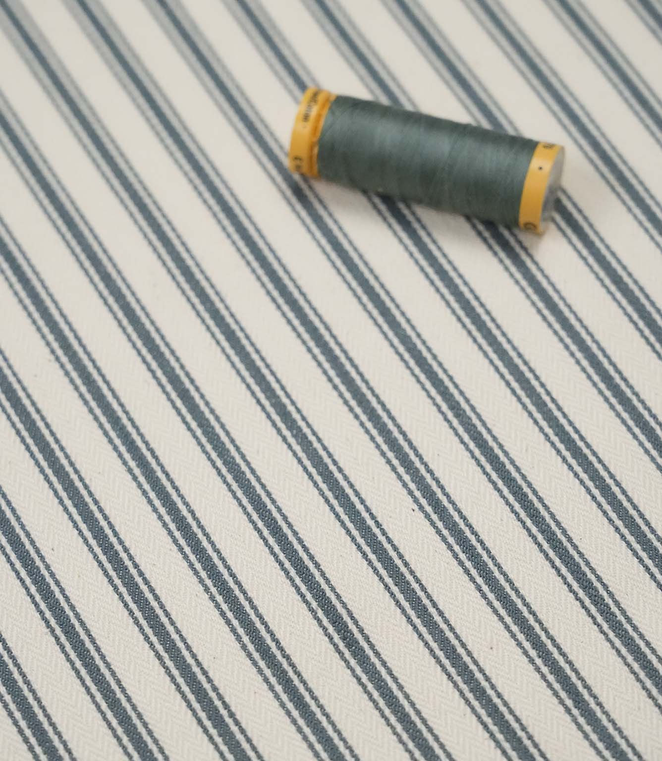Teal ticking stripe fabric with matching teal thread, ideal for upholstery, curtains, blinds and sewing projects.