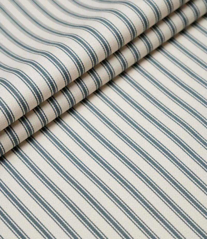 Layered folds of teal ticking stripe fabric displaying the fine herringbone weave and classic striped design.