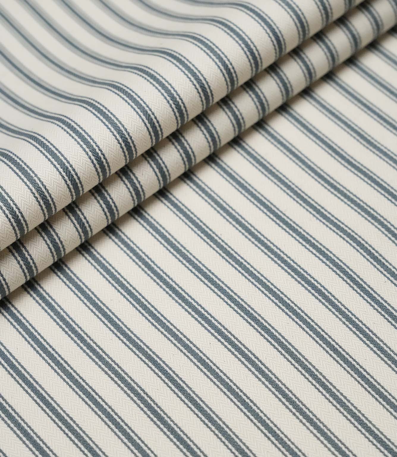Layered folds of teal ticking stripe fabric displaying the fine herringbone weave and classic striped design.