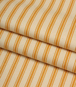 Folded ivory and turmeric yellow striped ticking fabric highlighting the woven herringbone texture and soft drape.