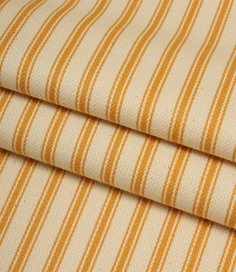 Folded ivory and turmeric yellow striped ticking fabric highlighting the woven herringbone texture and soft drape.