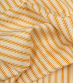 Gathered turmeric yellow ticking stripe fabric showing natural folds and durable woven finish.