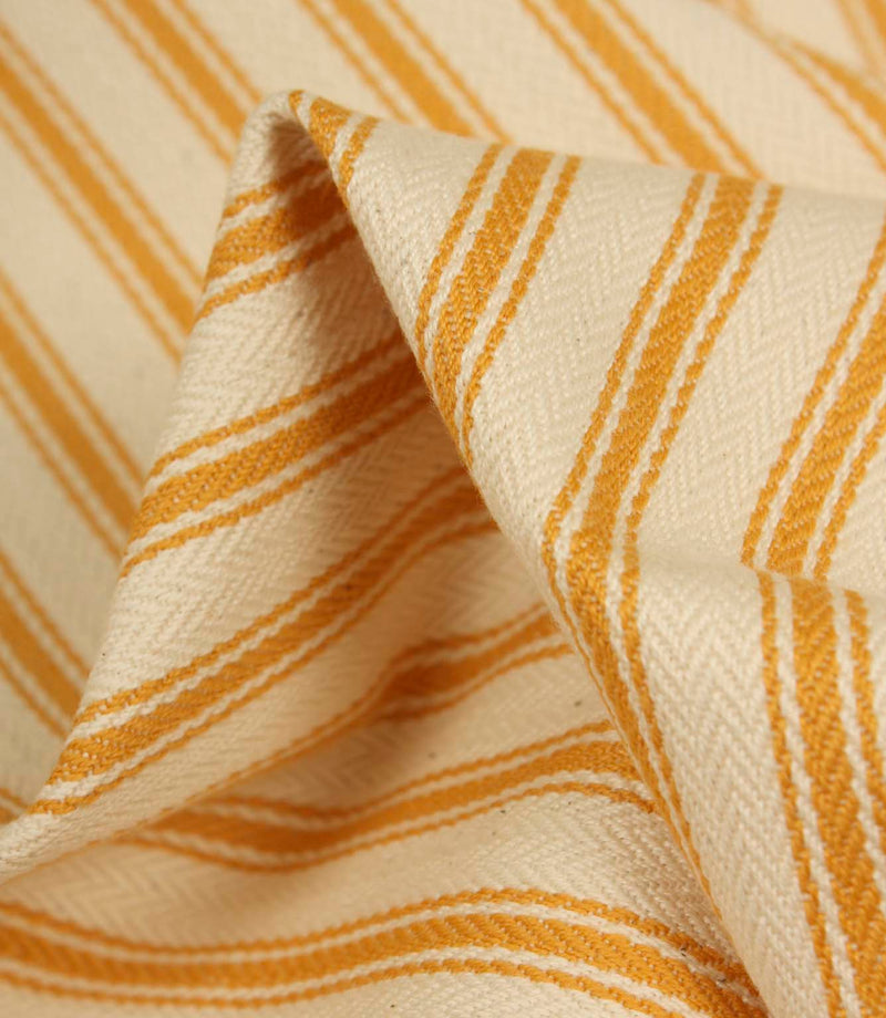 Detailed close-up of turmeric yellow striped ticking fabric with visible herringbone weave and soft textured folds.
