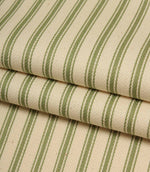 Folded ivory and warm green striped ticking fabric showcasing the woven herringbone texture and natural finish.
