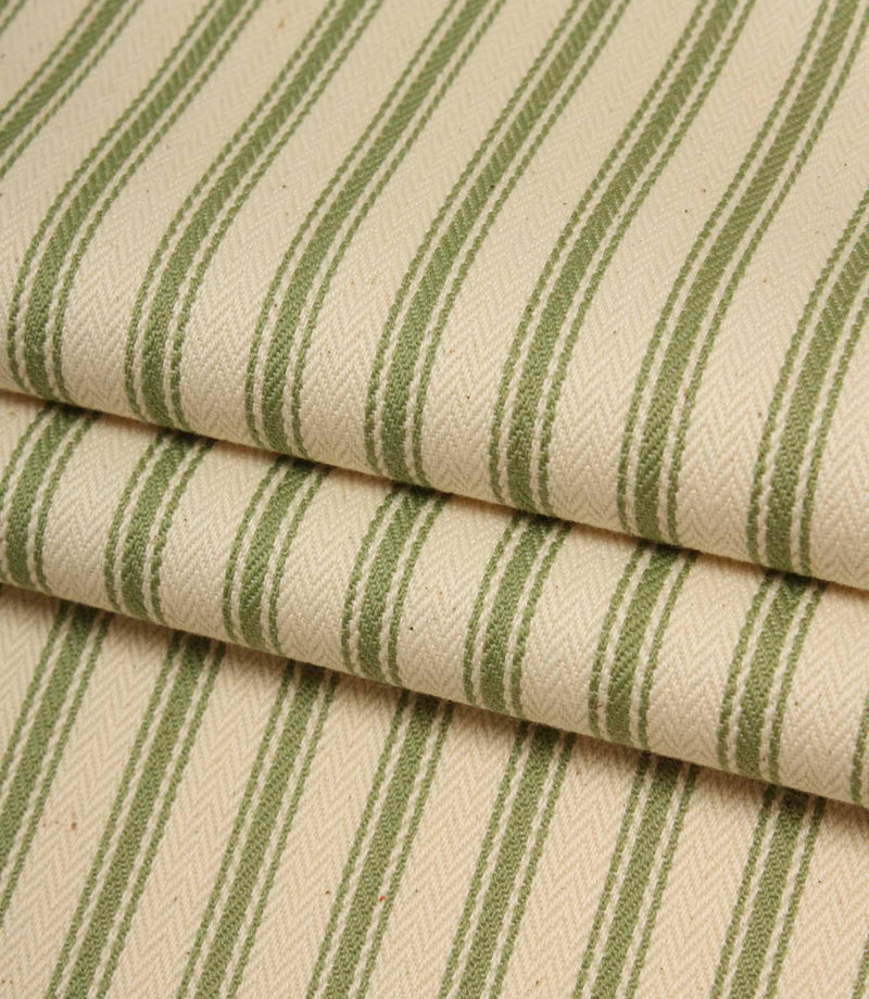 Folded ivory and warm green striped ticking fabric showcasing the woven herringbone texture and natural finish.