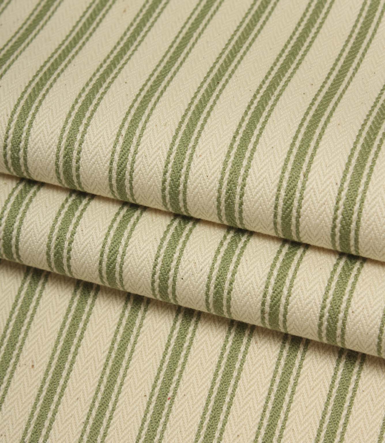 Folded ivory and warm green striped ticking fabric showcasing the woven herringbone texture and natural finish.