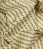 Draped warm green ticking stripe fabric highlighting soft folds and the timeless woven stripe pattern.