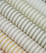 Collection of ticking stripe fabrics in sage green, duck egg blue, taupe, mustard and terracotta colourways, each featuring a classic striped design on an ivory herringbone weave.