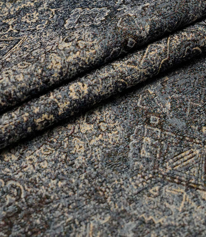 Folded blue Keshan tapestry upholstery fabric showcasing the detailed distressed design and woven texture.