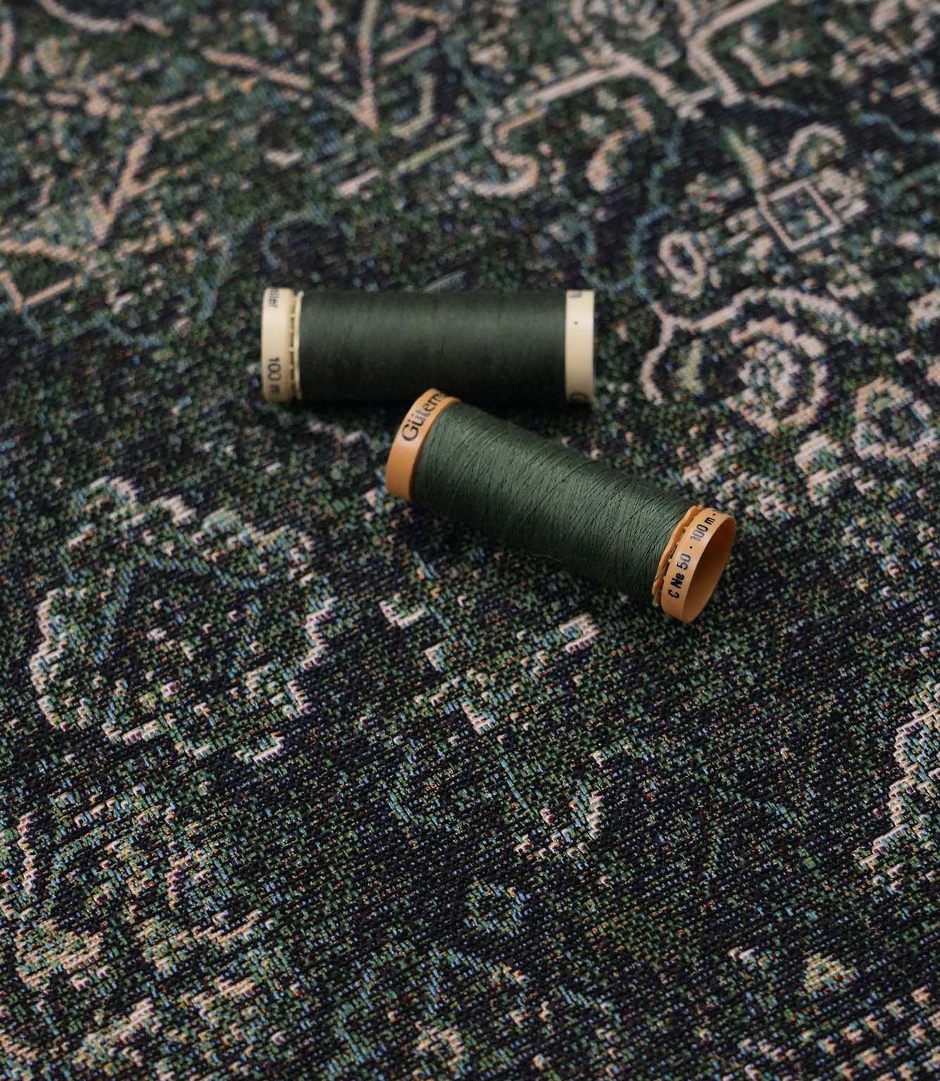 Green Keshan tapestry fabric with coordinating green sewing threads, ideal for upholstery, curtains and soft furnishing projects.