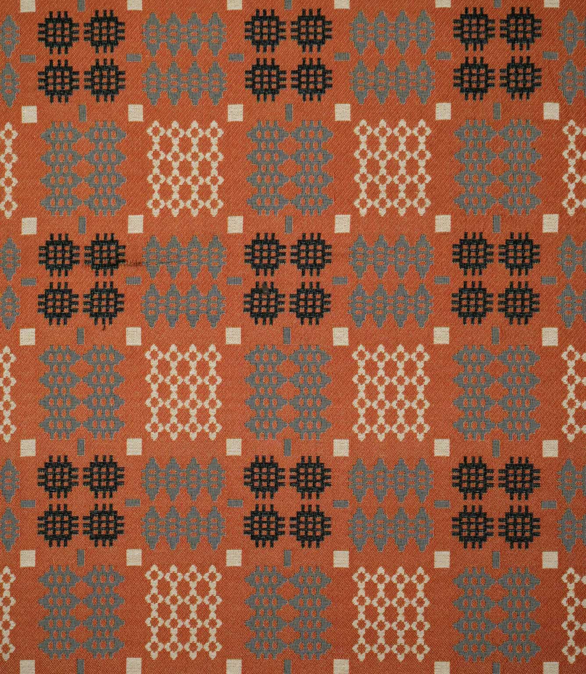 Kinfolk fabric shown flat, featuring a repeating geometric pattern in terracotta orange, charcoal black, soft grey and cream.