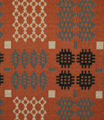 Close-up of Kinfolk fabric showing the woven texture and detailed geometric motifs in cream, grey and black on a terracotta orange background.