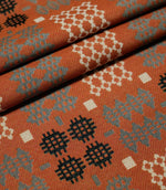 Kinfolk fabric arranged in neat folds, showing the scale and repetition of the geometric pattern in terracotta orange, grey, black and cream.