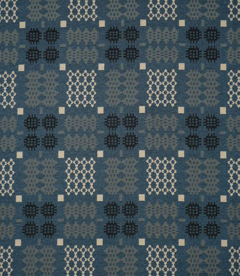Kinfolk geometric fabric in warm terracotta orange with repeating black, grey and cream woven-style motifs.