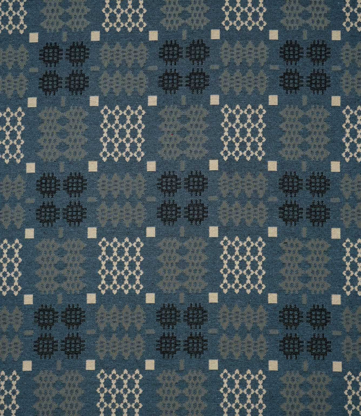 Kinfolk geometric fabric in warm terracotta orange with repeating black, grey and cream woven-style motifs.