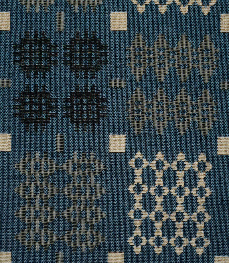 Close-up of Kinfolk fabric showing geometric black, grey and cream motifs against a terracotta orange ground.