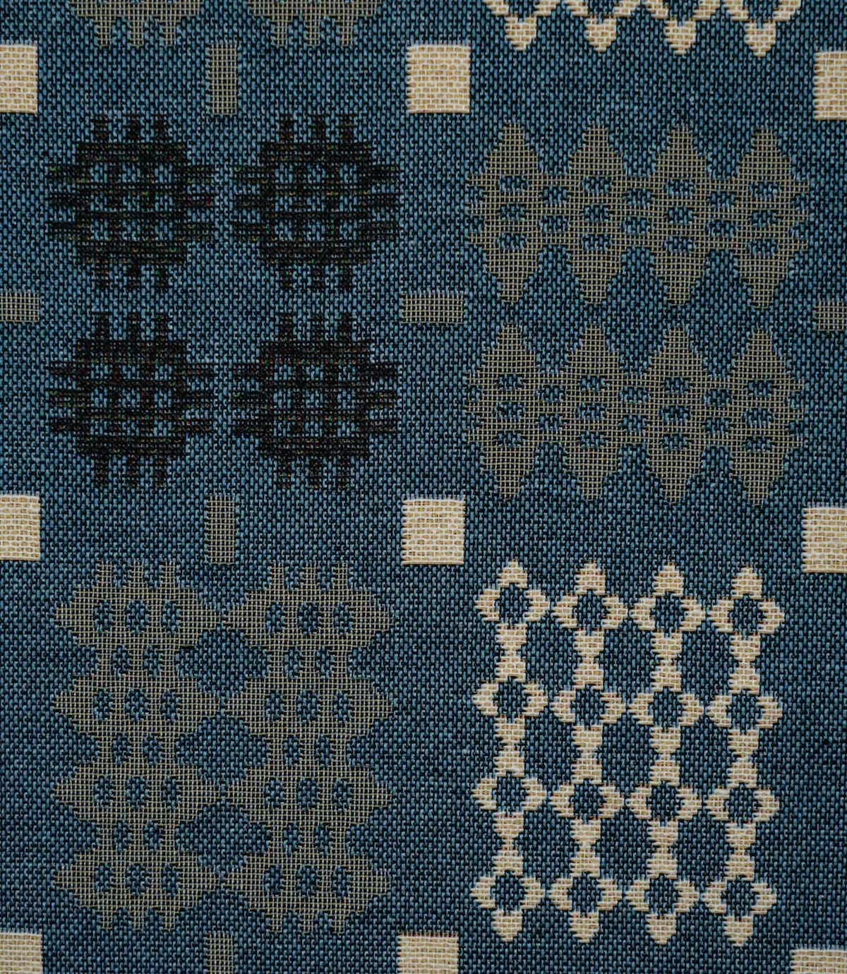 Close-up of Kinfolk fabric showing geometric black, grey and cream motifs against a terracotta orange ground.