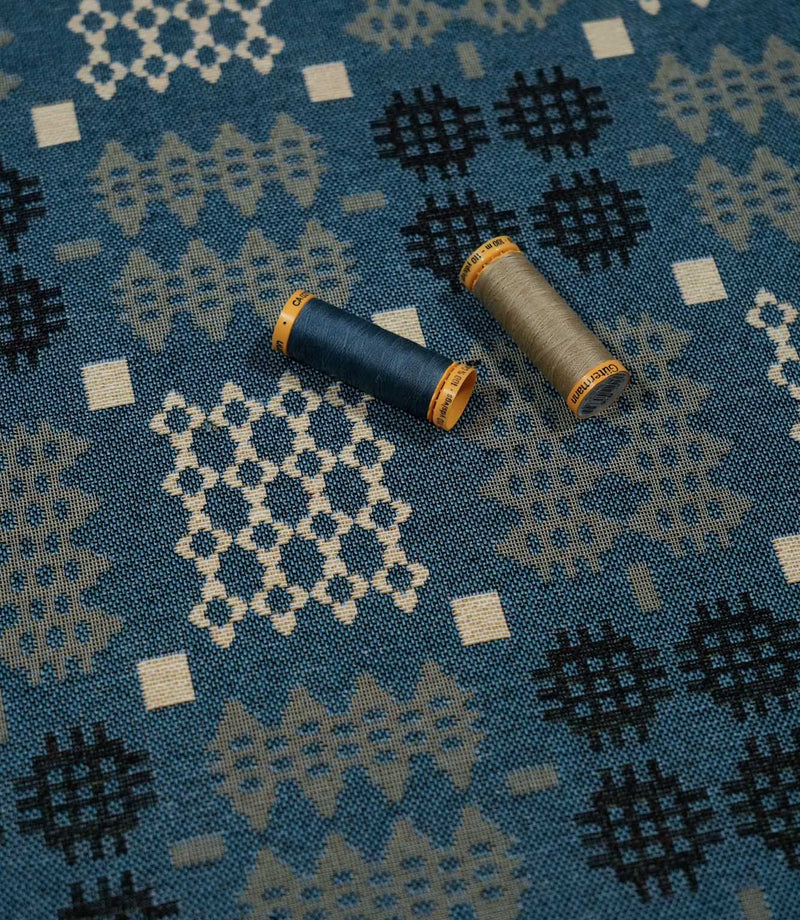 Kinfolk geometric fabric in terracotta orange with coordinating thread spools highlighting its grey and orange tones.